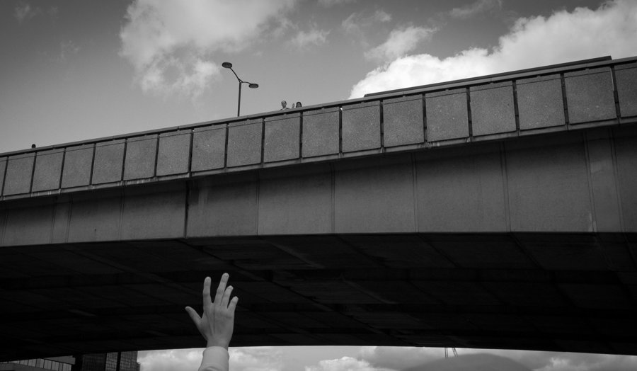 Una mano bajo un puente y un ave en el cielo